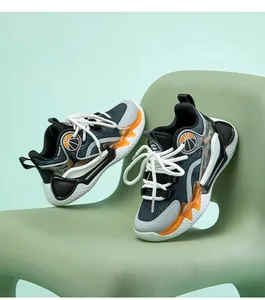 Stylische Kinder-Basketballschuhe mit orangefarbenen Akzenten auf einem grünen Stuhl