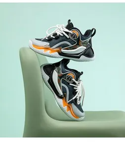 Stylische Basketballschuhe für Jungen auf grünem Stuhl mit orangefarbenen Details