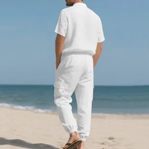 Vista trasera de un hombre con camisa de lino blanca y pantalones cargo en la playa soleada