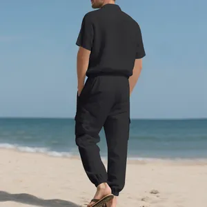 Vista trasera de un hombre con un conjunto de playa de lino negro en una playa de arena