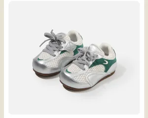 Detail view of silver and green toddler athletic shoes featuring breathable white mesh panels