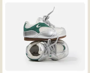 Detailed side view of silver and green toddler sneakers stacked on a neutral background