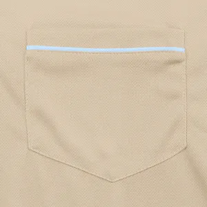 Primo piano della tasca sul petto di una polo da uomo beige con profili azzurri