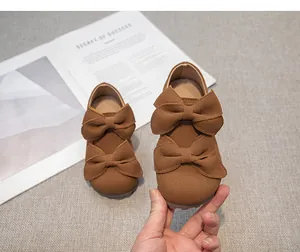 Nahaufnahme brauner Wildleder-Prinzessinnenschuhe für Mädchen mit doppelten Schleifen