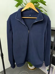Detailed view of a navy blue men's fleece quarter-zip pullover hanging on a wooden hanger.