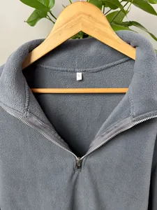 Close-up detail of grey men's fleece pullover with quarter-zip and stand collar