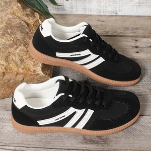 Close-up of black women's German trainers featuring white stripes and durable gum soles