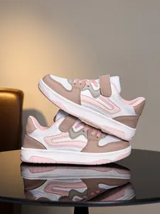 Vue latérale détaillée de baskets pour enfants roses et beiges sur une table miroir