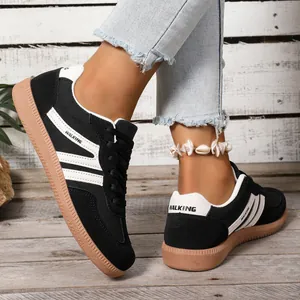 Detailed close-up of women's black German trainers with gum soles worn on a wooden floor.