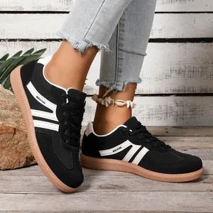 Side view of black German army trainer sneakers with white stripes and gum sole