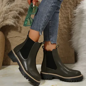 Vista detallada de botines Chelsea verde oliva para mujer con suela gruesa y jeans denim