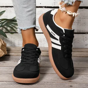 Women's classic black and white GAT casual sneakers with brown gum soles on rustic wood