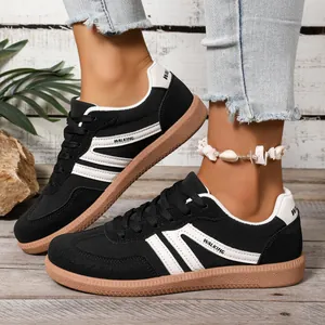 Detail view of women's black German Trainer shoes with white stripes and gum sole