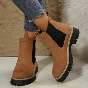 Primer plano de botas Chelsea de ante marrón con suela gruesa negra y paneles elásticos