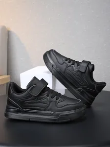 Vue détaillée de baskets de sport noires pour enfants avec bandes auto-agrippantes pour école.