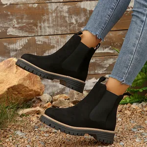 Vista lateral de botines Chelsea de ante negro con suela gruesa de goma y paneles elásticos.