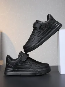 Gros plan de chaussures de sport noires pour enfants avec bandes auto-agrippantes en studio.