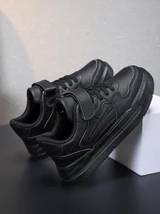 Gros plan de baskets noires pour enfants avec sangle velcro et finition en cuir