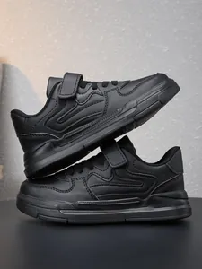 Détail rapproché de baskets de sport noires pour enfants avec sangles velcro et semelles antidérapantes