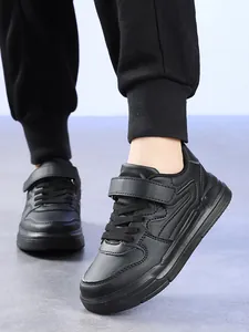Gros plan de baskets noires pour enfants avec sangle velcro et lacets résistants