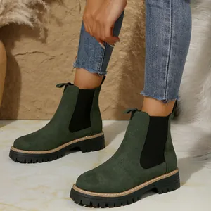 Detalle de elegantes botines Chelsea de ante verde oscuro con suela gruesa en modelo
