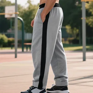 Detail view of men's heavyweight grey sweatpants with black side stripe and loose fit.
