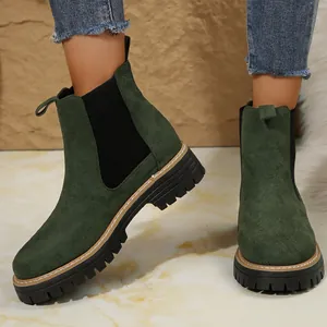Botines Chelsea de ante verde con suela gruesa, combinados con vaqueros para otoño.