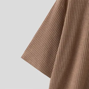 Macro view of textured brown ribbed knit fabric and sleeve stitching on a loose casual t-shirt