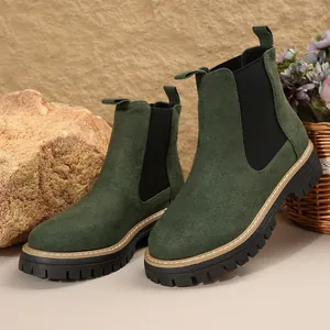 Primer plano de botines Chelsea de ante verde con suela de goma gruesa y bandas elásticas.