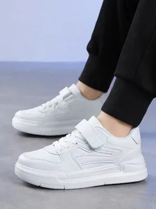 Vue latérale de baskets blanches pour enfants portées avec un jogging noir