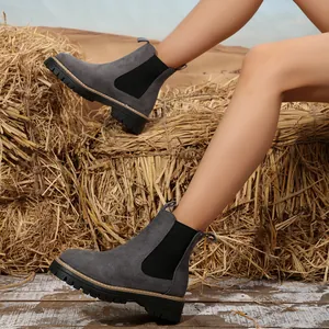 Botas Chelsea de ante gris para mujer con suelas gruesas de plataforma en un entorno rústico