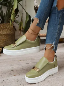 Detail view of stylish olive green platform slip-on shoes featuring a gold metal buckle