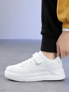 Gros plan de baskets blanches pour garçons avec bande velcro et semelle souple.