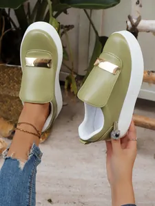 Detailed macro shot of olive green platform loafers featuring a gold metal bar decoration