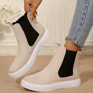 Detalle de botines Chelsea beige con suela blanca gruesa y paneles elásticos laterales.