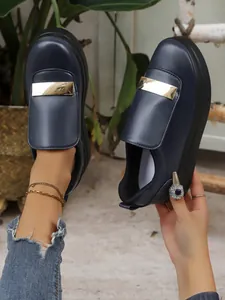 Detail shot of navy blue platform loafers featuring a stylish gold metal bar and platform sole