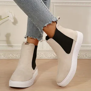 Primer plano de botas Chelsea de ante beige con suelas blancas gruesas y elásticos.