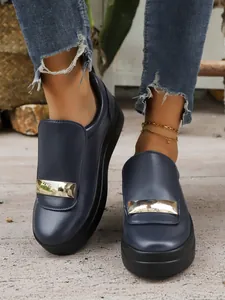 Detail of dark blue slip-on loafers with a stylish gold metal bar accent on the front.