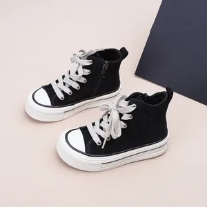 Gros plan de baskets montantes en toile noire pour enfants avec semelles blanches épaisses.