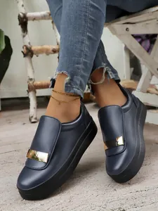 Close-up view of navy blue platform slip-on shoes featuring a stylish gold metallic buckle detail