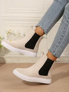 Primer plano de elegantes botines Chelsea de ante beige con suela de goma blanca