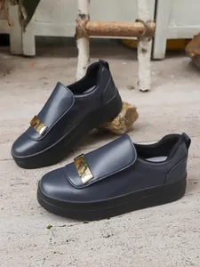 Detail of dark blue women's platform slip-on shoes with metallic gold buckle
