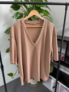 Detail view of a loose ribbed knit V-neck T-shirt with half sleeves in a taupe color.