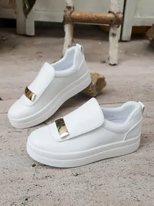 Detailed view of white platform slip-on shoes with gold metal buckle decoration