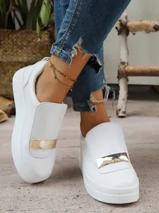 Detailed view of white platform slip-on shoes with elegant gold buckle on feet