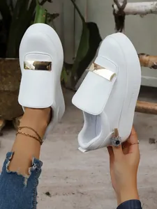 Close-up of white platform loafers with gold metal bar accents and thick soles
