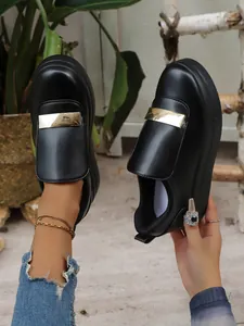 Detailed close-up of women's black platform slip-on shoes with gold metal buckle