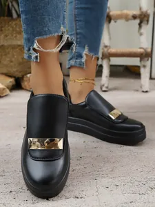 Close-up of black platform loafers with gold metal detail for women