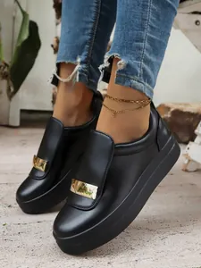 Close-up of black platform slip-on loafers with gold metal bar decoration