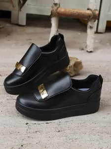 Close-up of black platform slip-on loafers for women with a gold metallic buckle detail.